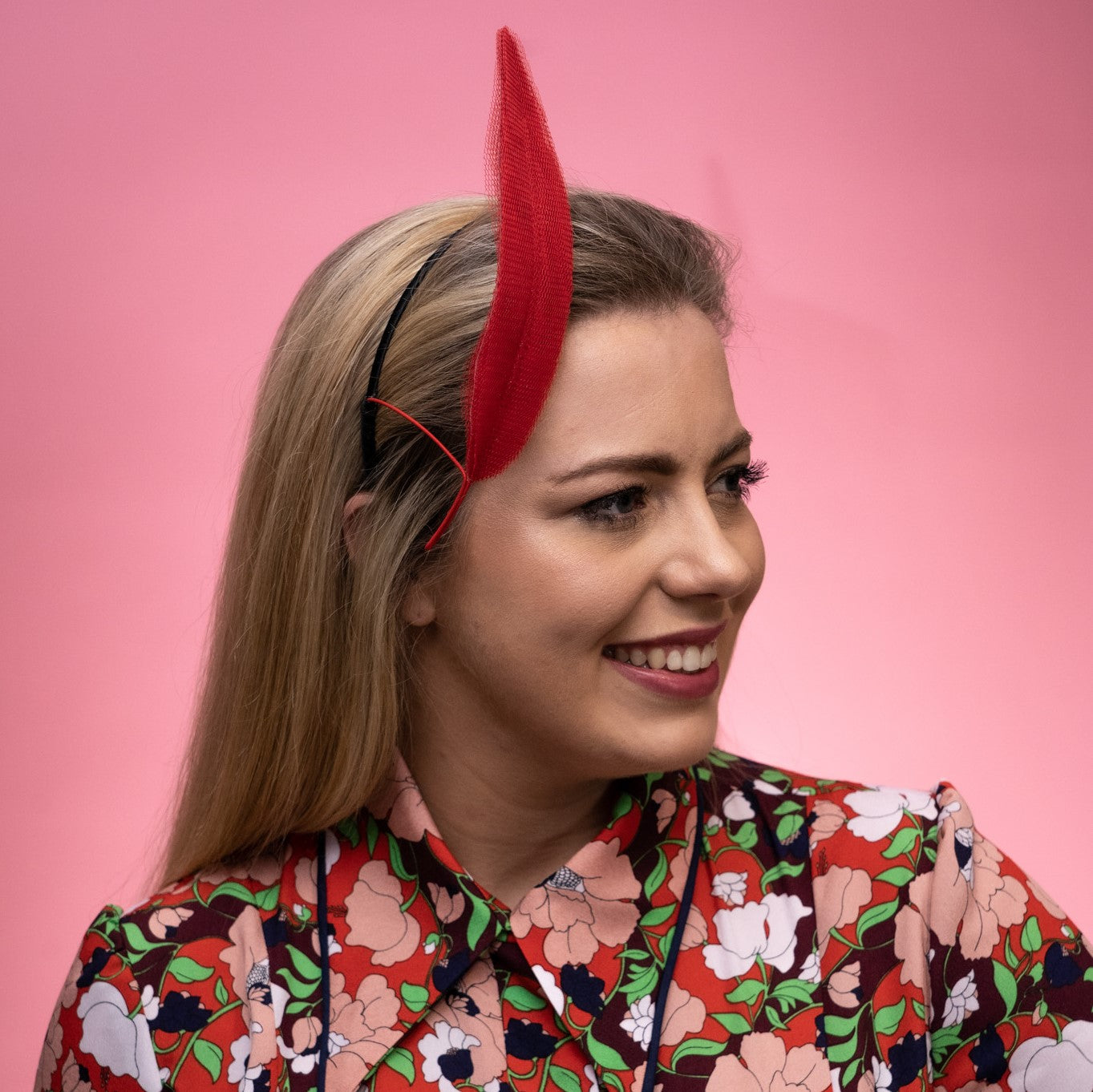 A side view of the Alba Headband in red. This photo shows that the floating tulle feather is secured to the head using a headband. Created by Melbourne based Lauren J Ritchie Millinery.